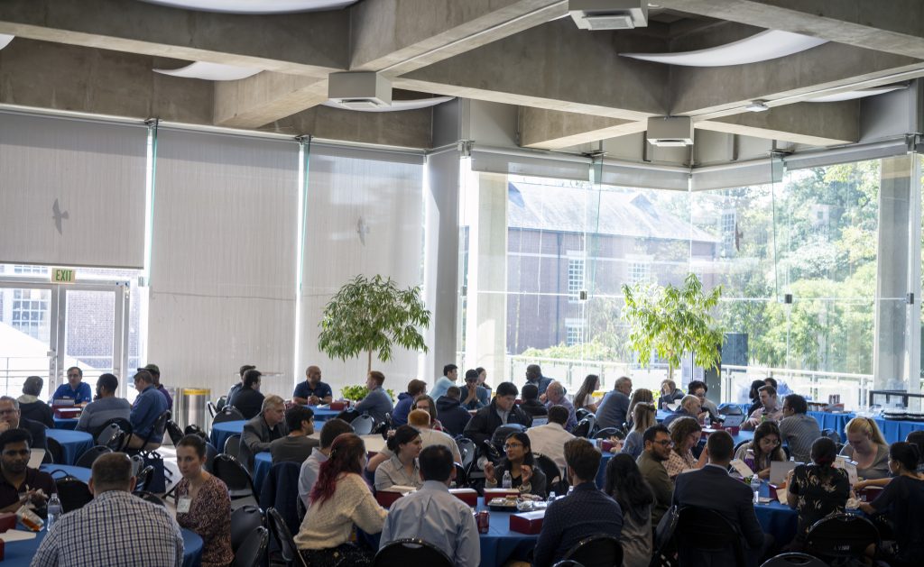 graduate students seated at round tables and networking in Glass Pavilion